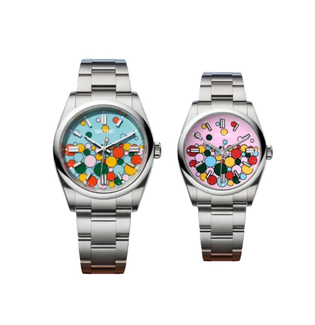 Two Seikojust Mod watches, one with a blue dial and the other with a pink celebration dial, both featuring a colorful geometric pattern and a stainless steel bracelet. Features 904L premium grade stainless steel and sapphire scratch proof glass with an automatic movement.