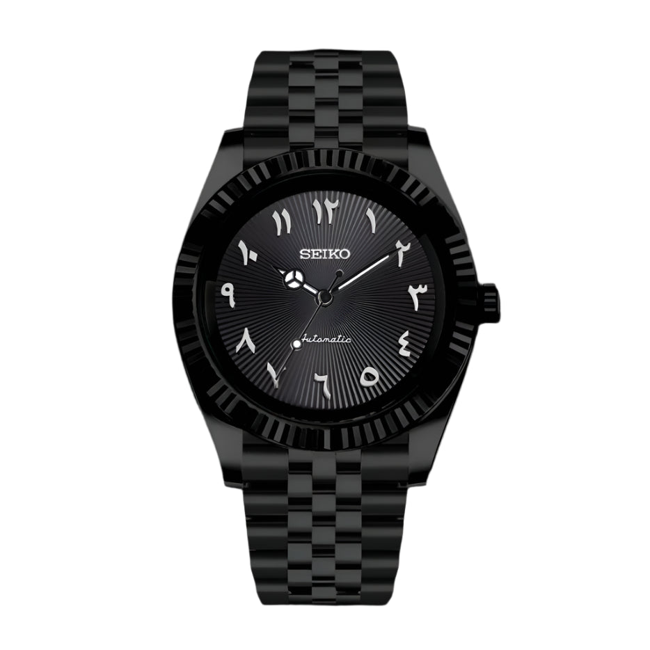 A black Seikojust Seiko Mod watch with a black band and dial, featuring Arabic numerals and a crystal case back.